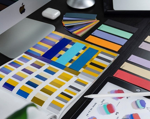 Image of color palettes on a desk with a computer.