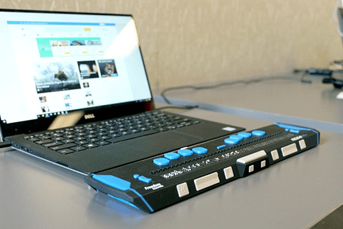 Image of a laptop with a refreshable braille display and special keyboard attachment. 