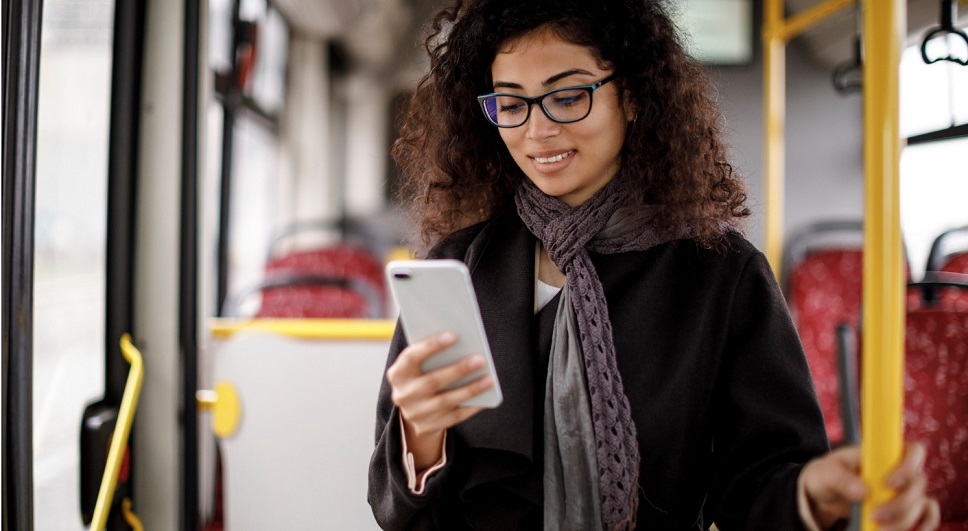 young woman traveling by bus and using smart phone